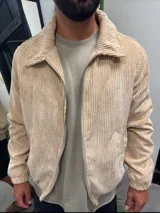 Campera de pana color beige con cierre frontal completo, cuello clásico y puños elásticos. Presenta un diseño de textura acanalada con bolsillos laterales.