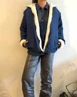 Campera azul de jean con interior de corderito blanco, cierre frontal y bolsillos laterales.