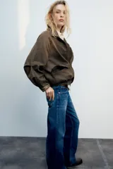 Chaqueta encerada color marrón con efecto lavado, cuello subido y manga larga. Cuenta con bolsillos frontales de plastrón y cierre de cremallera oculto por solapa con botones a presión. Los puños reversibles dejan ver un forro interior con estampado a cuadros.