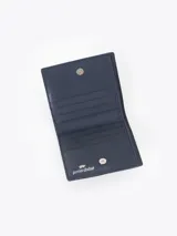 Mini billetera de cuero vacuno color rojo, con diseño grabado de pequeñas mariquitas en el frente y un aplique metálico en forma de corazón. Cuenta con un interior funcional con espacios organizadores para tarjetas.