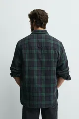 Camisa de corte regular fit confeccionada en tejido doble de algodón, con diseño de cuadros en tonos verde y azul marino. Presenta cuello solapa, manga larga con puño abotonado, bolsillo plastrón en el pecho y cierre frontal con botones.