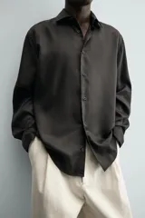 Camisa de corte relajado confeccionada en tejido fluido de lyocell. Presenta cuello solapa, manga larga con puños abotonados y cierre frontal con botones.