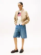 Campera bomber corta de color beige, con cierre frontal, cuello estilo béisbol, puños y bajo de punto canalé. Presenta un logo bordado en el pecho.