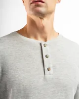 Remera tipo henley de manga larga confeccionada en tejido de algodón con textura mini piqué. Presenta un cierre frontal con tres botones y puños ajustados en las mangas.