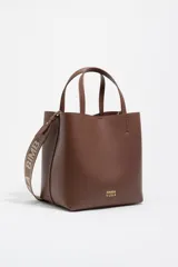 Bolso de mano tipo tote de Bimba y Lola, color marrón, confeccionado en piel reconstituida. Presenta doble asa de mano, asa de tejido ajustable con logo de la marca, cierre de botón de presión y logo metálico frontal.