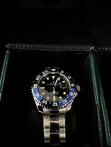 Reloj Rolex Submariner "Batman" con bisel giratorio unidireccional negro y azul, esfera negra con índices luminiscentes, lupa sobre la ventana de fecha y malla de acero inoxidable.
