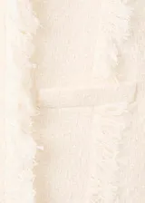 Chaqueta de tweed color crema con cuello redondo, cierre frontal con botones y dos bolsillos de parche delanteros. Presenta terminaciones deshilachadas y forro interior.