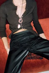 Pantalón largo de satén negro con pareo de encaje superpuesto en la cintura y lazada lateral. Cierre lateral con cremallera oculta.