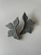 Par de aros con forma de media flor, color plateado con acabado brillante y detalle de strass en el centro. Cuentan con gancho de acero quirúrgico.