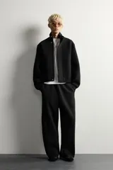 Pantalón de corte relajado confeccionado en tejido de algodón, con cintura elástica y detalle de pliegues estructurales en las perneras. Cuenta con bolsillos frontales y un bolsillo trasero de plastrón.