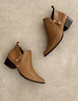 Botín corto color beige con textura símil piel de cocodrilo, taco de madera y laterales con corte en V.