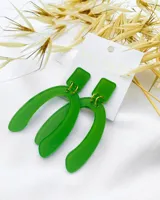 Aros colgantes de acrílico verde con forma de herradura invertida, unidos a un rectángulo superior por argollas doradas.