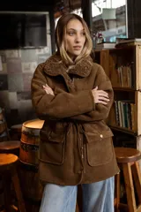 Campera de efecto gamuza color tostado con interior de corderito sintético. Presenta cierre frontal, bolsillos delanteros con solapa, cintura ajustable con cordón y puños con detalle de corderito.