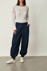 Pantalón tipo jean azul oscuro, de corte slouchy con pinzas en la cintura, bolsillos laterales y puños fruncidos con elástico en los tobillos.