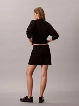 Shorts de felpa francesa color negro, con talle alto, cintura elástica y bolsillos laterales. Presenta el logo de la marca bordado en el bajo.