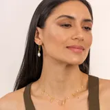 Collar dorado con cadena fina y dijes colgantes de perlas barrocas y piezas irregulares con textura.