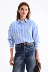 Camisa oversize confeccionada en mezcla de lino y viscosa, con diseño a rayas verticales en tonos celeste y blanco. Cuenta con cuello clásico, cierre frontal de botones, hombros caídos y mangas largas con puños abotonados.