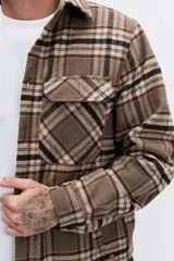 Campera tipo sobrecamisa de franela a cuadros en tonos marrones y beige, con interior forrado en corderito blanco. Presenta cierre frontal, bolsillos en el pecho con solapa y mangas largas con puños abotonados.
