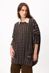 Sweater de punto con diseño de trenzas verticales en tonos negro y beige, corte holgado, cuello redondo y bolsillos frontales con el logo de la marca bordado.