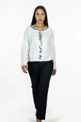 Cardigan blanco de tejido de punto con cuello redondo y cierre frontal decorado con lentejuelas plateadas circulares. Presenta mangas largas y un corte recto.
