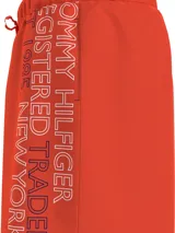 Short de baño Tommy Hilfiger color naranja, con cintura elástica ajustable mediante cordón. Presenta un diseño liso con el logo de la marca estampado verticalmente en el lateral izquierdo.