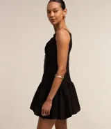 Vestido corto negro con escote cuadrado, breteles finos, corte a la cintura y falda balonê. Presenta un corte en el pecho y cierre con cremallera en la espalda.