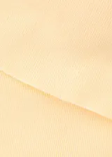 Top asimétrico de punto fino color amarillo pálido, con diseño de un solo hombro y corte recto ajustado al cuerpo.