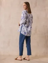 Blusa estampada con flores azules sobre fondo blanco, marca Floral & Ivy. Tiene cuello a la base con escote en V y aplique de botones. Las mangas son tres cuartos con puño y botón. Presenta tajos en las costuras laterales.