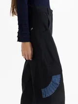 Pantalón de gabardina color marrón, de tiro alto y silueta estructurada. Cuenta con volados de denim azul aplicados sobre los bolsillos plaqué laterales y bolsillos plaqué traseros con remache dorado.