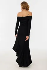 Vestido midi negro con escote off-shoulder, mangas largas y falda con volados asimétricos.