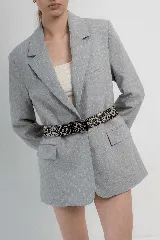 Cinturón de cuero color camel con múltiples tachas metálicas redondas y cuadradas, y hebilla metálica de estilo rústico.