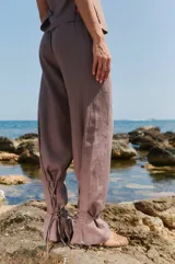 Pantalón color café de lino y rayón, con bolsillos delanteros, elástico en la cintura trasera y lazos en las botamangas para ajustar.