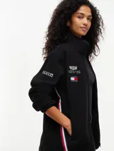 Campera de tejido polar negra Tommy Hilfiger, con cuello chimenea y cierre de cremallera. Presenta diseño Global Stripe en los laterales, bolsillos abiertos en diagonal y el logo de la marca junto con el de Cadillac Formula 1 Team en el pecho.
