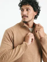 Sweater de punto color tostado, con cuello alto y cierre frontal parcial con botones. Diseño de manga larga con puños y ruedo acanalados.