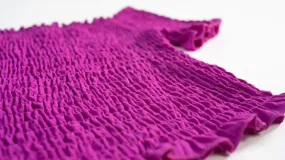 Top de color azul con diseño fruncido en toda la prenda, escote estilo hombros caídos y mangas cortas con terminación de volados.