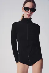 Chaqueta de punto negra con cuello subido y cierre frontal con cremallera, de manga larga y diseño ajustado.