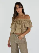Top corto de estilo off-shoulder con diseño de volados en capas, confeccionado en tela liviana con textura.
