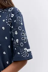 Remera de corte oversize color marrón con estampado tipo bandana en color blanco. Presenta cuello redondo y mangas cortas amplias.