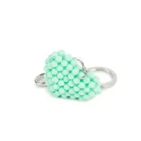 Llavero con dije en forma de corazón confeccionado con pequeñas cuentas esféricas de color turquesa. Incluye una argolla metálica y un gancho de mosquetón plateado.