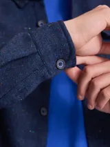 Overshirt de textura tipo tweed en color marrón, con cuello clásico, cierre frontal de botones y bolsillo en el pecho.