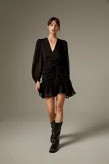Vestido corto negro de poliéster, con escote en V cruzado, mangas largas abullonadas con puños ajustados y detalle de lazo en la cintura.