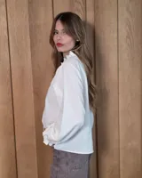 Camisa de manga larga con estampado de cuadros en tonos azules y rojizos. Presenta un cuello alto con volados y puños elásticos con detalle de volado en el extremo. Cierre frontal con botones ocultos.