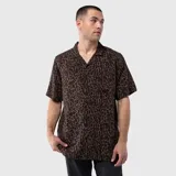 Camisa de manga corta con cuello cubano, confeccionada en viscosa con estampado animal print en tonos marrones y negros. Presenta un bolsillo frontal en el pecho y cierre de botones.