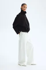 Campera negra de efecto neopreno, con cuello chimenea, cierre frontal completo y hombros caídos. Presenta un diseño holgado con pliegues en el bajo y mangas largas.
