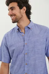 Camisa de manga corta color azul piedra melange, con cuello abotonado y cierre frontal con botones en contraste.