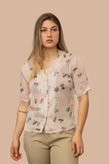 Camisa de gasa color salmón con estampado de flores y hojas en tonos pasteles, con cuello en V y cierre con botones.