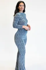 Conjunto de dos piezas compuesto por una remera de manga larga y un pantalón tipo palazo, confeccionado en tejido elastizado con acabado brillante y textura lineal. La remera presenta cuello redondo y ajuste al cuerpo, mientras que el pantalón posee un corte recto y holgado.