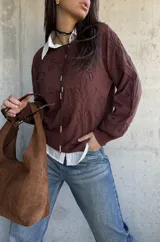 Sweater de tejido de punto color chocolate, con diseño de flores bordadas en relieve, cuello redondo y mangas largas con puños elásticos.