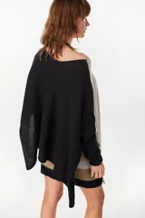 Poncho oversize de tejido de punto con hilos de lurex, color negro, con escote redondo y aberturas laterales en las mangas.