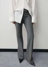 Pantalon de vestir gris de corte acampanado, con tiro medio, trabillas para cinturon, cierre oculto y bolsillos de ribete en la parte posterior.